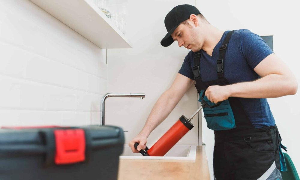 Plumber unclogging kitchen sink with professional force pump cleaner.